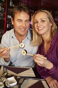 Couple Enjoying Sushi In Restaurant
