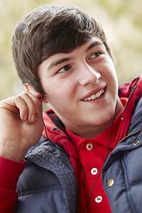 Teenage Boy Wearing Earphones And Listening To Music Wearing Winter Clothes