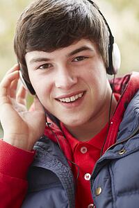 Teenage Boy Wearing Headphones And Listening To Music Wearing Winter Clothes