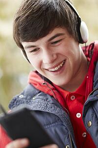 Teenage Boy Wearing Headphones And Listening To Music Wearing Winter Clothes