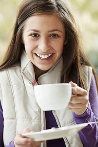 Teenage Girl In Outdoor CafÃ© With Hot Drink Wearing Winter Clothes