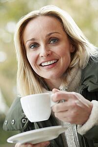 Woman In Outdoor CafÃ© With Hot Drink Wearing Winter Clothes