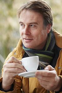 Man In Outdoor CafÃ© With Hot Drink Wearing Winter Clothes