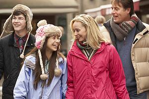 Teenage Family Walking Along Snowy Town Street In Ski Resort