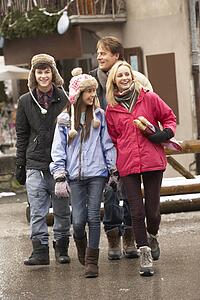 Teenage Family Walking Along Snowy Town Street In Ski Resort